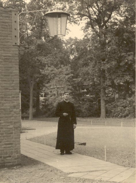 Pater F. Stams bewondert de nieuwe smeedijzeren lantaarn aan het schoolgebouw (voorjaar 1956)